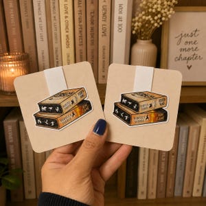 May include: Two identical rectangular stickers featuring a stack of two books titled Fourth Wing and Iron Flame by Rebecca Yarros. The stickers are attached to light beige cardstock backings. The book spines show dragon silhouettes.
