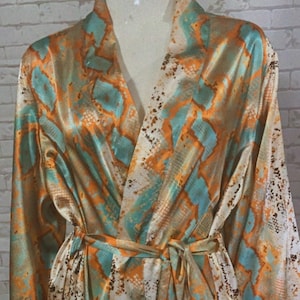 May include: A long-sleeved robe with a snakeskin print in shades of orange, teal, and brown. The robe has a tie belt and a V-neck.