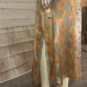 May include: A long, flowing dress with a snakeskin print in shades of orange, blue, and white. The dress has a side slit and a fitted bodice.