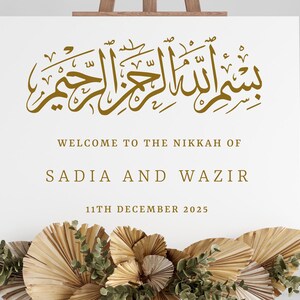 Pu&ograve; includere: Un cartello bianco con calligrafia dorata che recita "بسم الله الرحمن الرحيم" e il testo "Benvenuti al Nikkah di Sadia e Wazir 11 dicembre 2025".