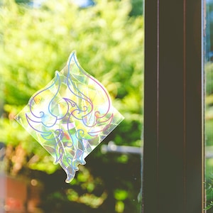 May include: A colorful, iridescent window cling with a geometric design. The cling is shaped like a diamond and features a pattern of overlapping, curved shapes. The design is outlined in blue, pink, and yellow.
