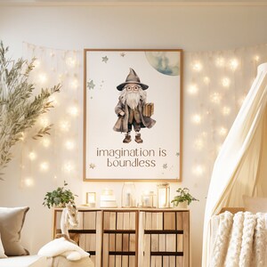 Puede incluir: Una habitación de bebé con una cuna blanca, un sofá blanco, un armario de madera y una impresión enmarcada de un mago con el texto "imagination is boundless".