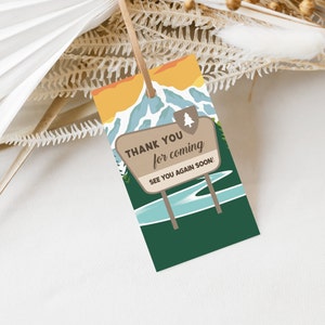 May include: A brown and tan thank you tag with a green background. The tag features a cartoon illustration of a mountain range with a lake and a sign that reads "Thank you for coming. See you again soon!"