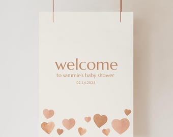 Könnte beinhalten: Ein weißes Willkommensschild mit dem Text "welcome to sammie's baby shower 02.14.2024" in brauner Schrift. Das Schild ist mit braunen Aquarellherzen verziert.