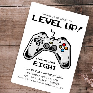 May include: A white birthday party invitation featuring a cartoon video game controller. The text reads "Brandon is ready to level up! Loading level... Eight. Join us for a birthday bash Saturday June 15, 1pm 1234 First Street, Denver. Please RSVP to Kim at kim@gmail.com"