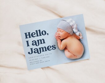 May include: A blue and white baby announcement card with the text "Hello, I am James" in a retro font. The card also includes the baby's name, birthdate, weight, and the names of the parents.