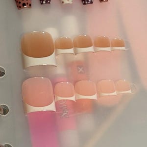 May include: A set of press-on nails featuring two distinct styles. The top row includes five long coffin-shaped nails with brown and dark maroon polka dot patterns. The bottom two rows feature ten square-shaped nails with a classic French manicure design.