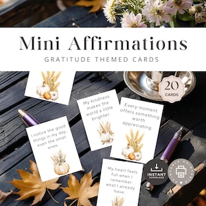 May include: Mini Affirmations gratitude themed cards. The image shows several white cards with affirmations, each featuring a watercolor illustration of pumpkins and wheat. The cards are on a dark wooden surface with fall leaves and pens.