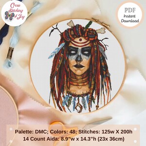 May include: A cross-stitch pattern featuring a woman with face paint, feathers, and dreadlocks, framed in a wooden hoop. The design includes the text "Cross Stitching 4 Joy" and "PDF Instant Download". The pattern size is 8.9"w x 14.3"h.