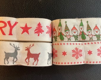 May include: Four rolls of white fabric ribbon with different Christmas-themed designs. The designs include a red star, a Christmas tree, snowflakes, reindeer, and a row of elves. One roll has the word "Merry" printed on it.