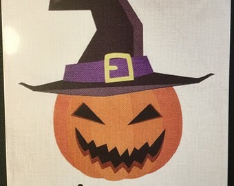 Könnte beinhalten: Ein weißes Metallschild mit einem Cartoon-Kürbis, der einen Hexenhut trägt. Der Kürbis hat ein verschmitztes Grinsen und das Schild sagt "Trick or Treat".