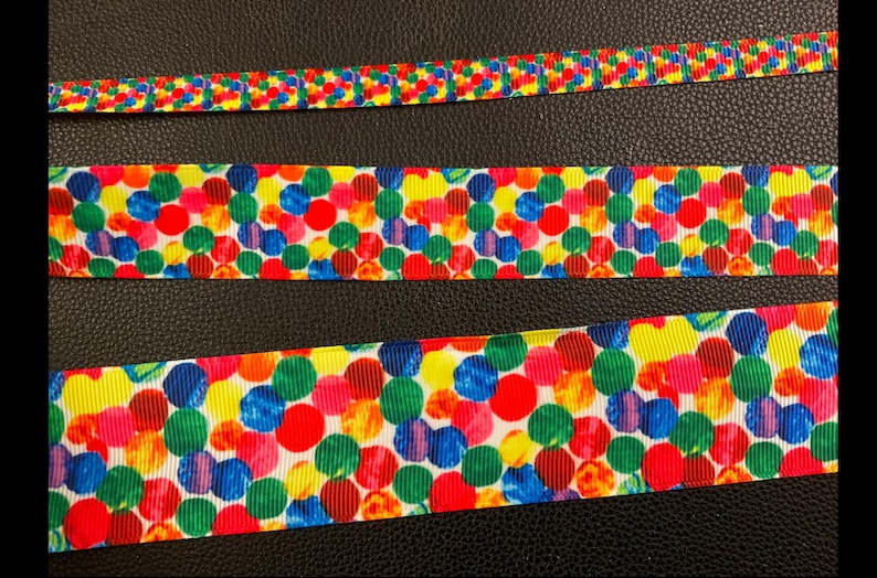 May include: Three different widths of colorful ribbon with a pattern of multi-colored circles on a white background.