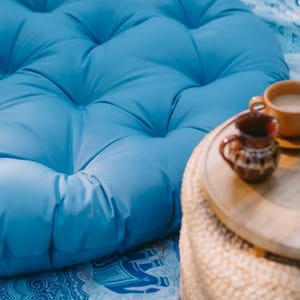 Light blue round outdoor cushion by Patuu Living, made from water-repellent fabric suitable for outdoor use. Designed for terraces, balconies and garden seating, it adds a soft Scandinavian touch to modern outdoor and indoor spaces. Comfortable and durable, perfect for patio lounging, cozy balcony corners or relaxed summer gatherings.