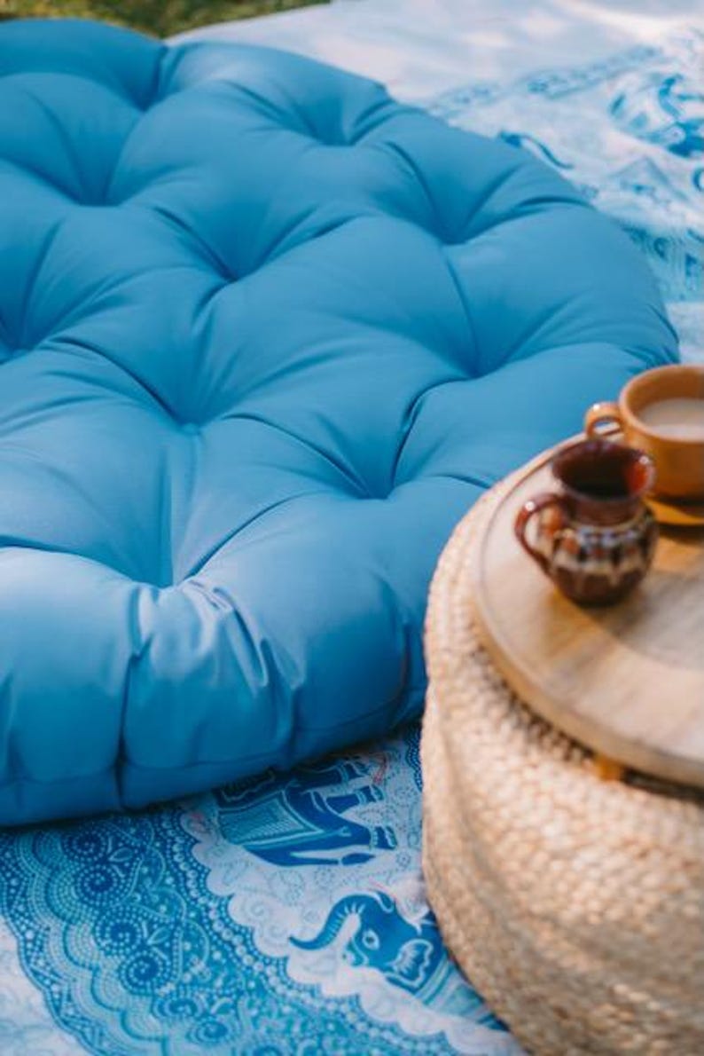 Light blue round outdoor cushion by Patuu Living, made from water-repellent fabric suitable for outdoor use. Designed for terraces, balconies and garden seating, it adds a soft Scandinavian touch to modern outdoor and indoor spaces. Comfortable and durable, perfect for patio lounging, cozy balcony corners or relaxed summer gatherings.