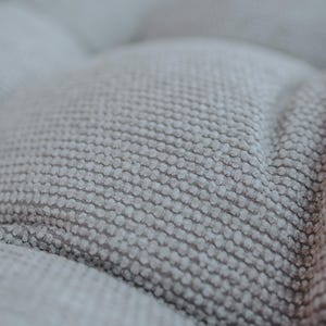 Cream white outdoor cushion set on a bench, featuring a bottom seat cushion and matching backrest in French mattress style. Made from high-quality EU-produced bouclé-like fabric suitable for outdoor use. The material is water-repellent but not fully waterproof and can get wet occasionally. Also suitable for indoor spaces. Perfect for modern Scandinavian homes, A-frame houses, Portuguese terraces and bohemian Spanish villas.
