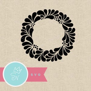 May include: Black floral wreath design with a circular shape, featuring stylized leaves and small berry-like details. The design is set against a neutral background. A logo with the letters "SN" and the word "SVG" is in the lower left corner.