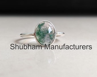 May include: A silver ring with a green and white moss agate oval stone.