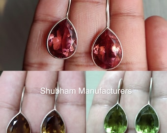 May include: A pair of silver dangle earrings with teardrop-shaped gemstones. The earrings are shown in three different colors: red, green, and brown.