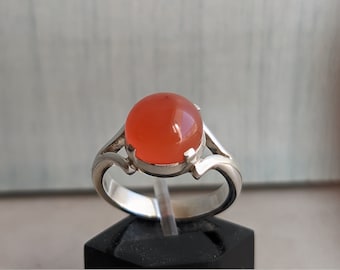 May include: A silver ring with a large, round, orange gemstone.