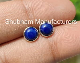 May include: A pair of silver stud earrings with round blue lapis lazuli gemstones. Shubham Manufacturers is printed on the background.