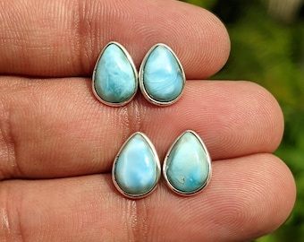May include: A pair of teardrop-shaped earrings with a light blue gemstone set in silver.
