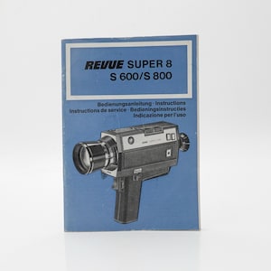 Puede incluir: Manual de instrucciones azul para una cámara de cine Revue Super 8 S 600/S 800. El manual presenta la imagen de la cámara, un cuerpo negro y plateado con una lente grande. El texto incluye "Bedienungsanleitung - Instructions".