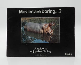 May include: A black book with the title "Movies are boring...?" in white text. The cover features a photo of a hippo in water. Below the photo is the text "A guide to enjoyable filming" and the author's name.