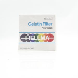 以下が含まれることがあります： Hellmaゼラチンフィルターの白いパッケージ。サイズは7.5 x 7.5 cmです。「Gelatin Filter」の青い文字、ブランド名、一連のカラーサークルがパッケージに表示されています。「Keep in cool dry place」の文字も表示されています。