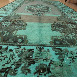 May include: A teal blue rug with a faded, intricate pattern in a darker shade of blue. The rug has a worn, vintage look.