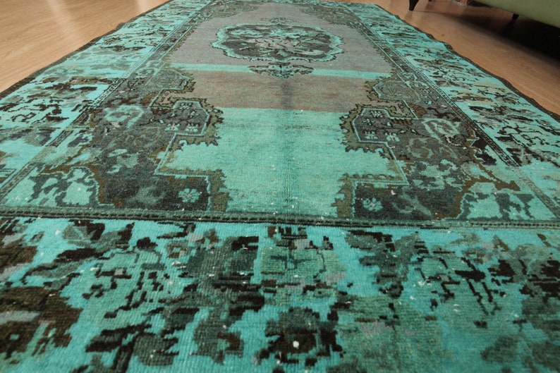 May include: A teal blue rug with a faded, intricate pattern in a darker shade of blue. The rug has a worn, vintage look.