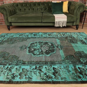 May include: A teal and gray vintage rug with a floral pattern in the center. The rug has a distressed look and is perfect for adding a touch of bohemian style to any room.