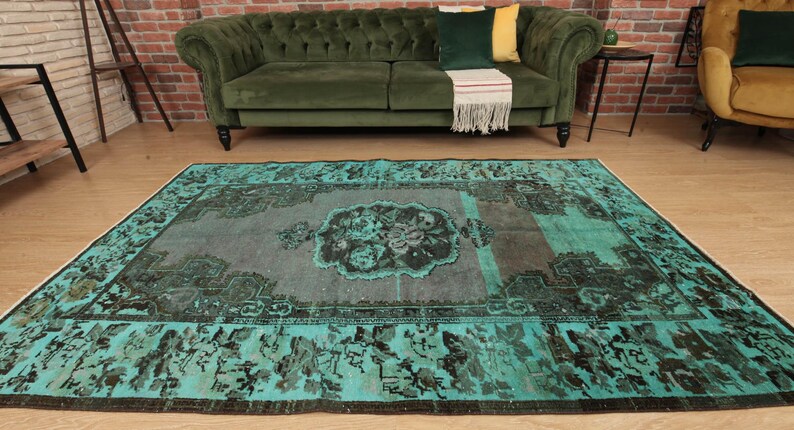 May include: A teal and gray vintage rug with a floral pattern in the center. The rug has a distressed look and is perfect for adding a touch of bohemian style to any room.