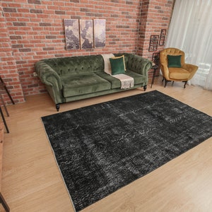 Pode incluir: Um tapete de &aacute;rea desgastado em preto e branco com um sof&aacute; de veludo verde escuro e uma poltrona amarela mostarda no fundo.