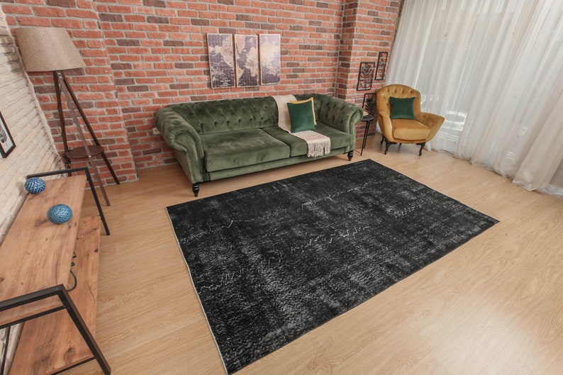 Pode incluir: Um tapete de &aacute;rea desgastado em preto e branco com um sof&aacute; de veludo verde escuro e uma poltrona amarela mostarda no fundo.