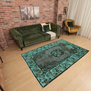 May include: A teal and black vintage rug with a floral pattern. The rug is laid out on a wooden floor in a living room setting.
