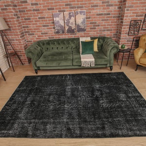 Pode incluir: Um tapete de &aacute;rea desgastado em preto e branco com um sof&aacute; de veludo verde e uma poltrona amarela mostarda em um ambiente de sala de estar.