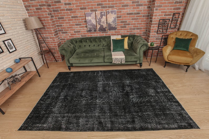 Pode incluir: Um tapete de &aacute;rea desgastado em preto e branco com um sof&aacute; de veludo verde e uma poltrona amarela mostarda em um ambiente de sala de estar.