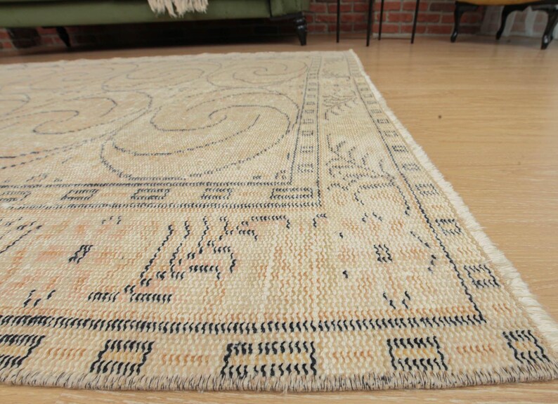 May include: A beige rug with a black and white geometric pattern. The rug has a fringe border.