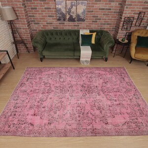 May include: A large rectangular area rug featuring a vibrant pink base color with an intricate, distressed-style black floral and botanical pattern throughout. The rug has a low-pile texture and a finished border, covering a significant floor space.