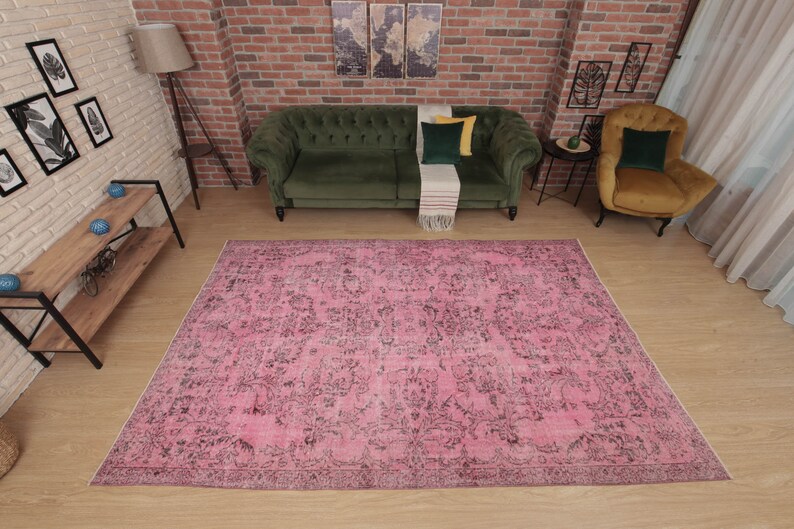 May include: A large rectangular area rug featuring a vibrant pink base color with an intricate, distressed-style black floral and botanical pattern throughout. The rug has a low-pile texture and a finished border, covering a significant floor space.