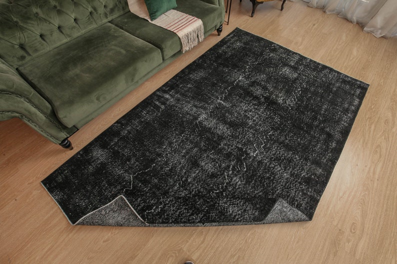 Pode incluir: Um tapete de &aacute;rea preto e branco com um visual desgastado e vintage. O tapete tem um padr&atilde;o sutil de linhas e redemoinhos brancos sobre um fundo preto.