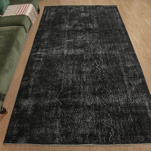Pode incluir: Um tapete preto e branco desgastado com um visual vintage. O tapete tem um aspeto desbotado e desgastado com um padr&atilde;o subtil.