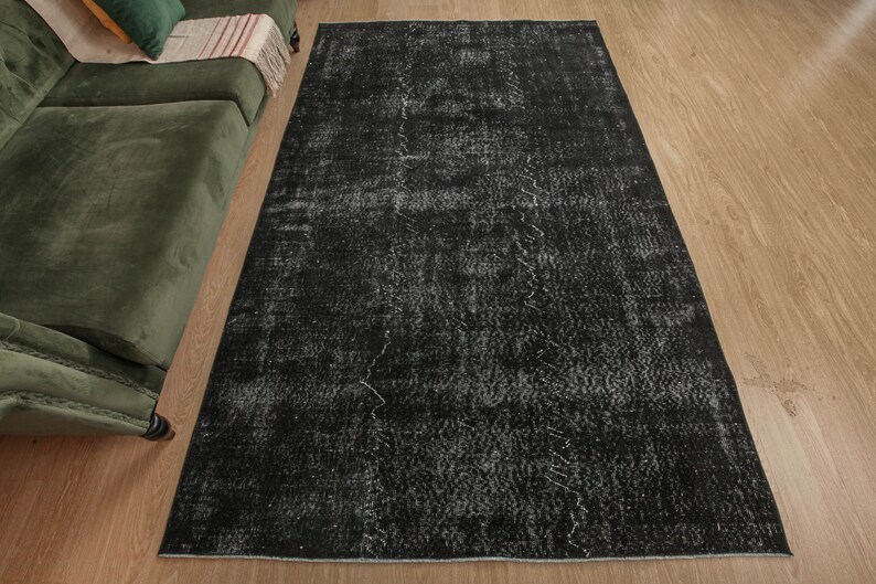 Pode incluir: Um tapete preto e branco desgastado com um visual vintage. O tapete tem um aspeto desbotado e desgastado com um padr&atilde;o subtil.