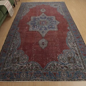 May include: A vintage rug with a faded red background and a blue and white floral pattern. The rug has a distressed look and is perfect for adding a touch of bohemian style to your home.