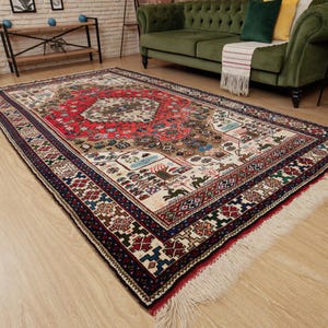 May include: A traditional Persian rug with a cream background and intricate red, blue, and green patterns. The rug has a fringe border and is laid out on a wooden floor.