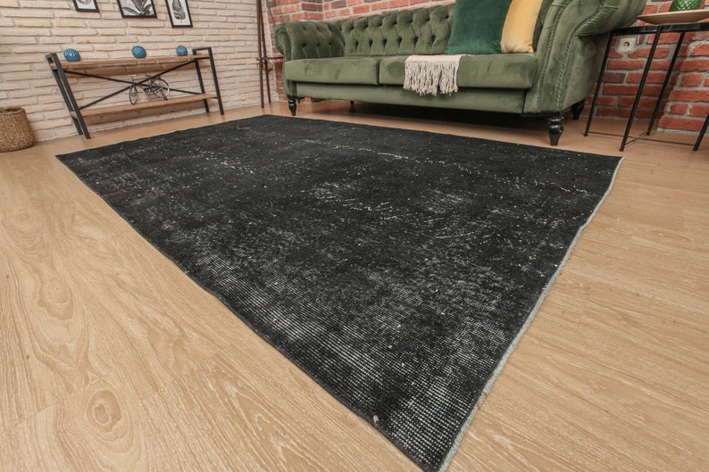 Pode incluir: Um tapete preto e branco desgastado com um padr&atilde;o sutil. O tapete est&aacute; colocado sobre um piso de madeira clara.