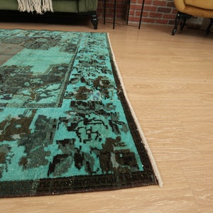May include: A teal and brown vintage rug with a geometric pattern. The rug has a fringe border.