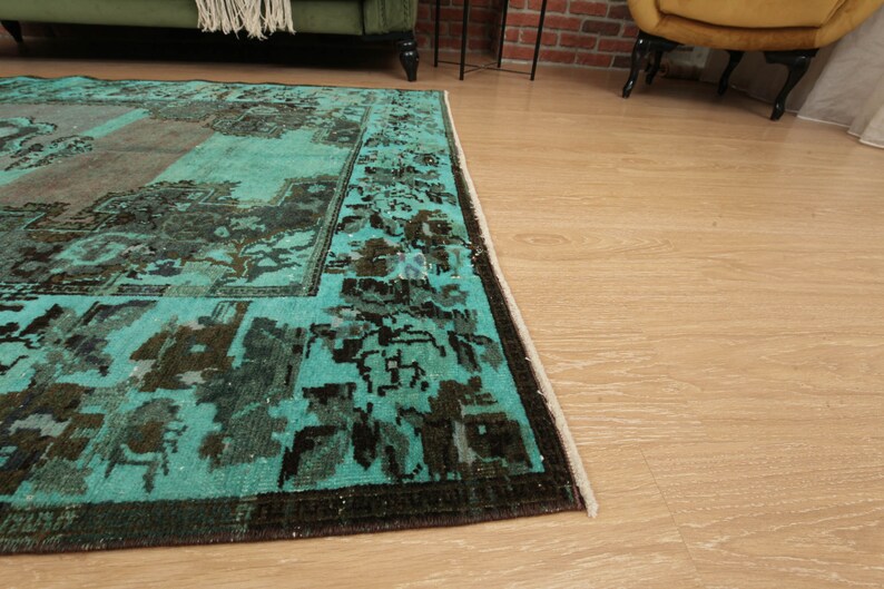 May include: A teal and brown vintage rug with a geometric pattern. The rug has a fringe border.