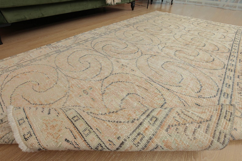 May include: A beige rug with a black and white geometric pattern. The rug has a distressed look and is rolled up.