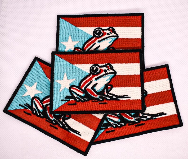 May include: Rectangular embroidered patches featuring the Puerto Rican flag design with a frog illustration. The patches have a red and white striped background, a blue triangle with a white star, and a frog with red and white stripes.